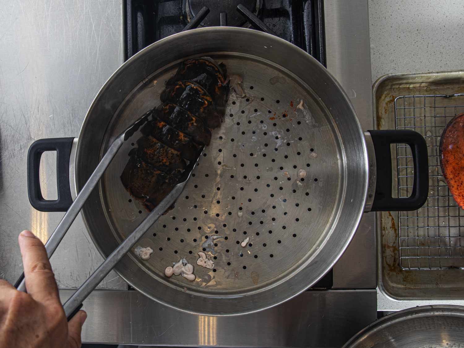  A lobster tail being added to a steamer on the stove top