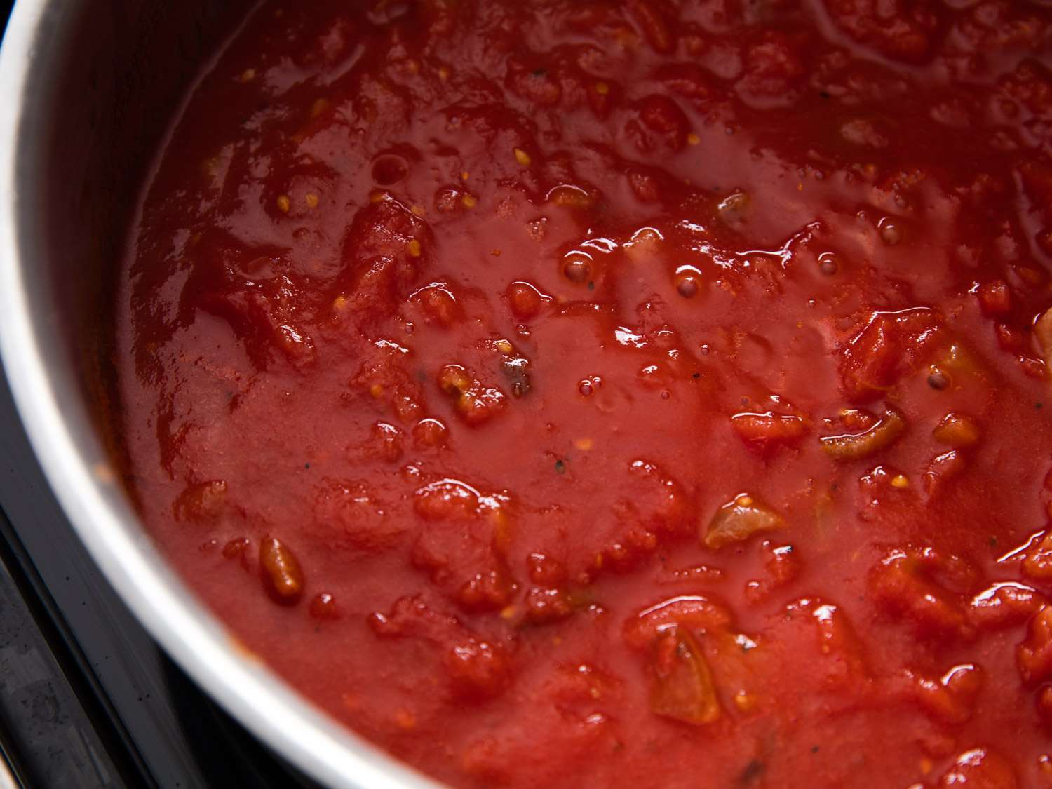 Close-up overhead shot of a pot of tomato sauce simmering. 