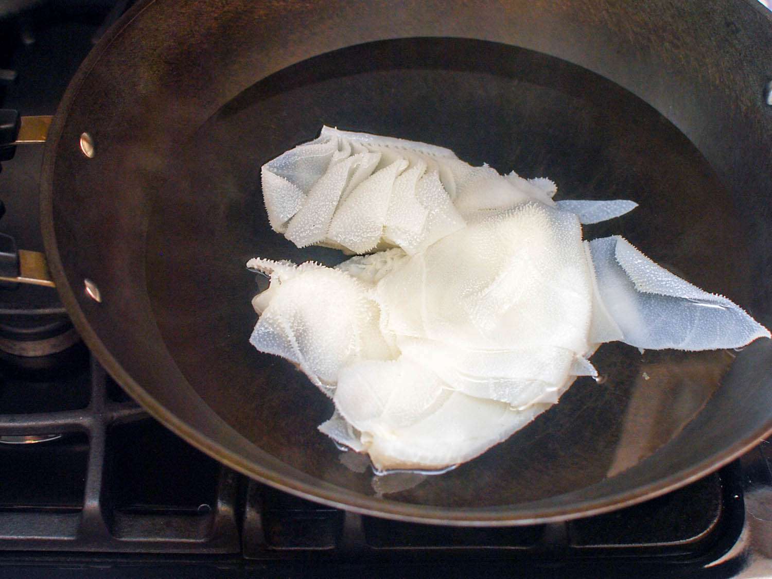 The tripe is briefly simmered with water in a wok.