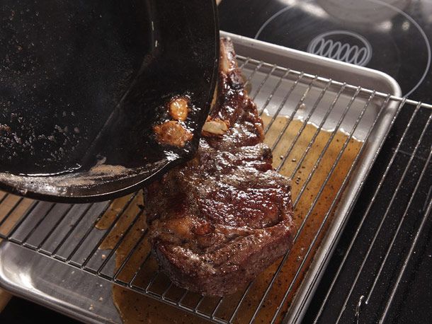 Pouring pan drippings over a dry-aged ribeye