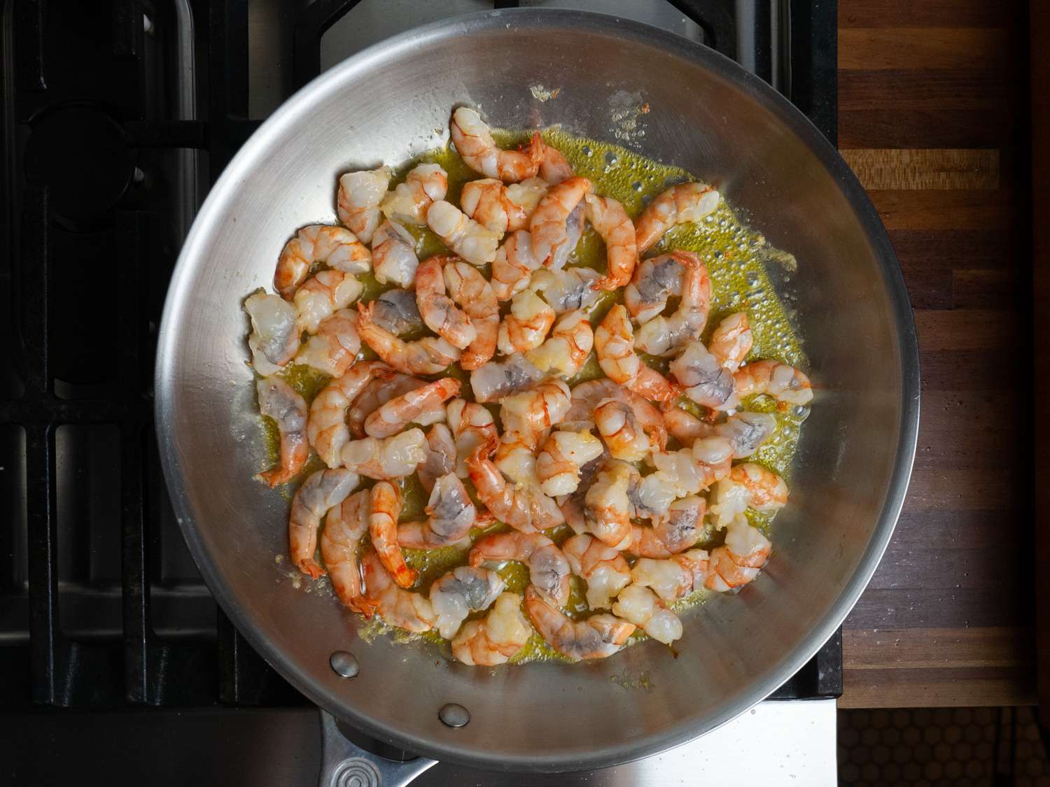 Shrimp cooking with butter and garlic in a skillet.