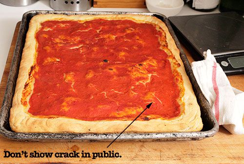 A finished tomato pie. The sauced surface has cracks from where the sauce dried out and exposed a bit of dough. One of these sites is labeled: "Don't show crack in public."