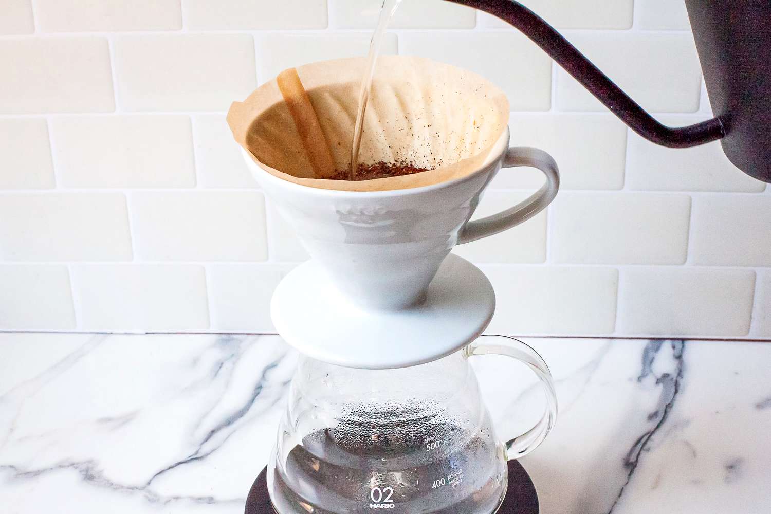 Pour-over coffee brewing setup with water pouring into a filter of grounds