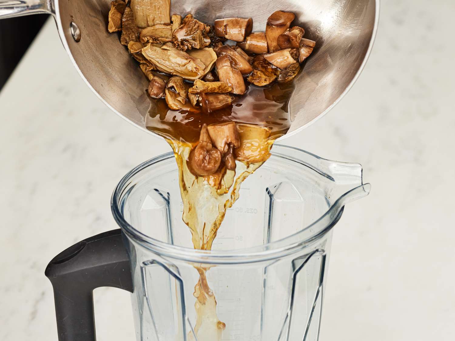 Mushroom mixture pouring from pot into blender