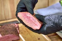 A person holds up meat cooked in the Pit Barrel Cooker Co. Classic Pit Barrel Cooker