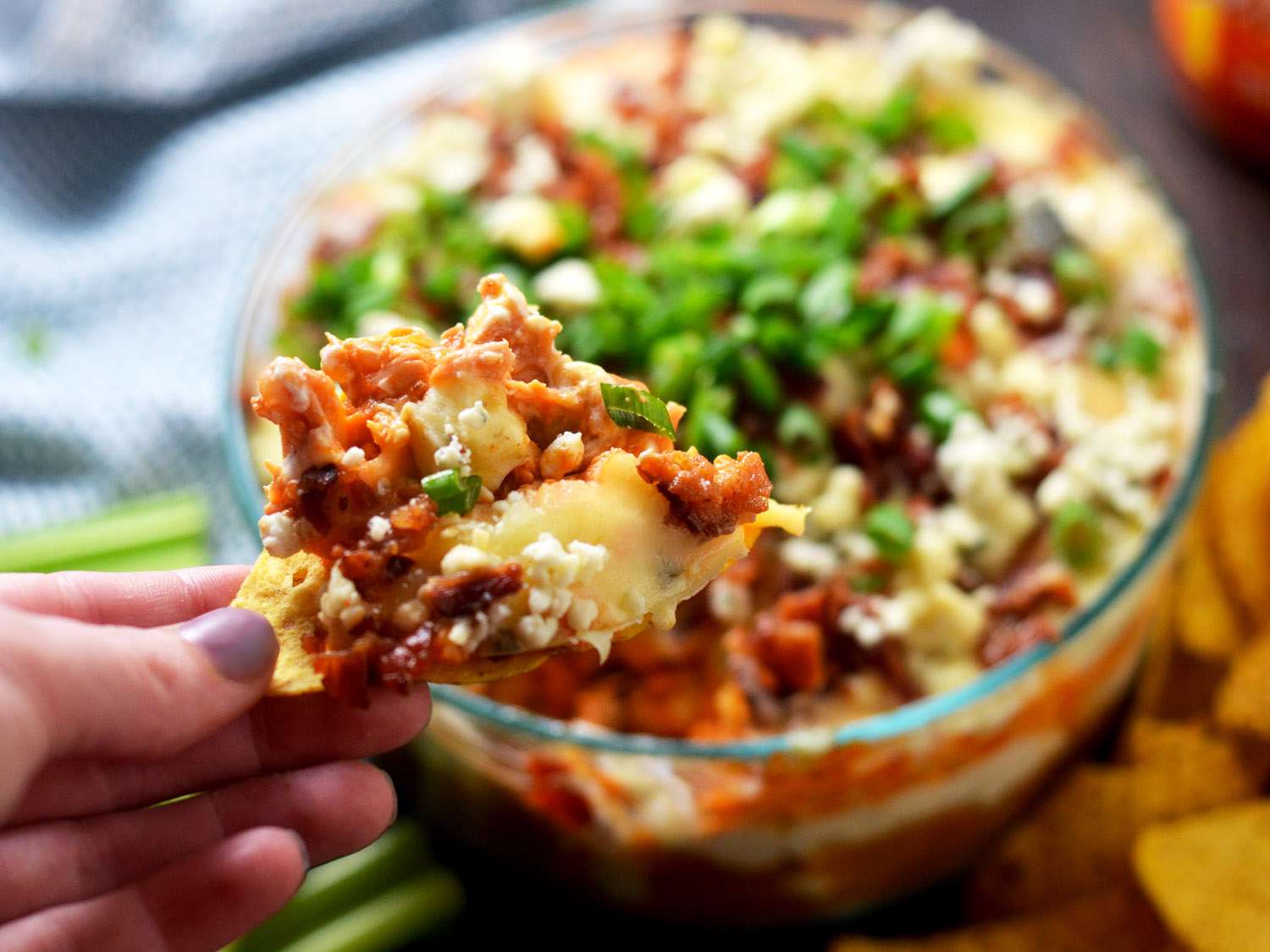 A chip topped with the finished dip is held up to the camera.