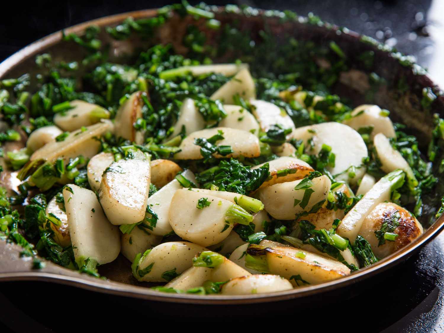 Sautéed Hakurei (Japanese) turnips tossed with chopped blanched greens in a skillet.