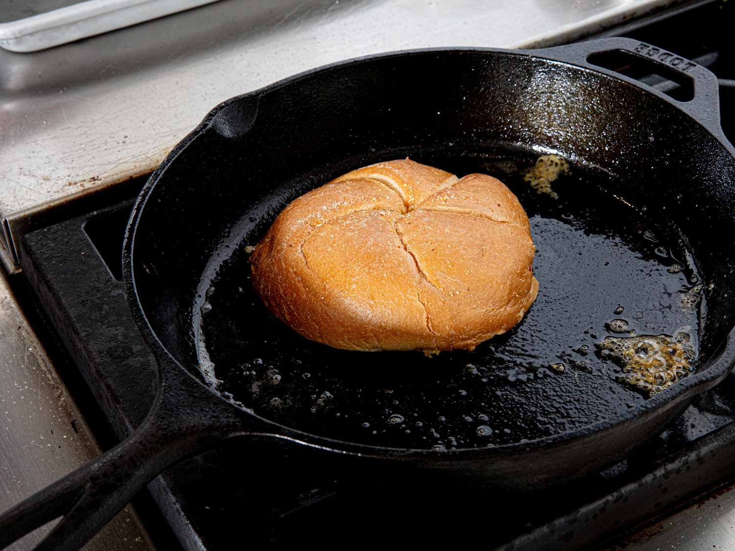 A Kaiser roll mops up juices in a pan.