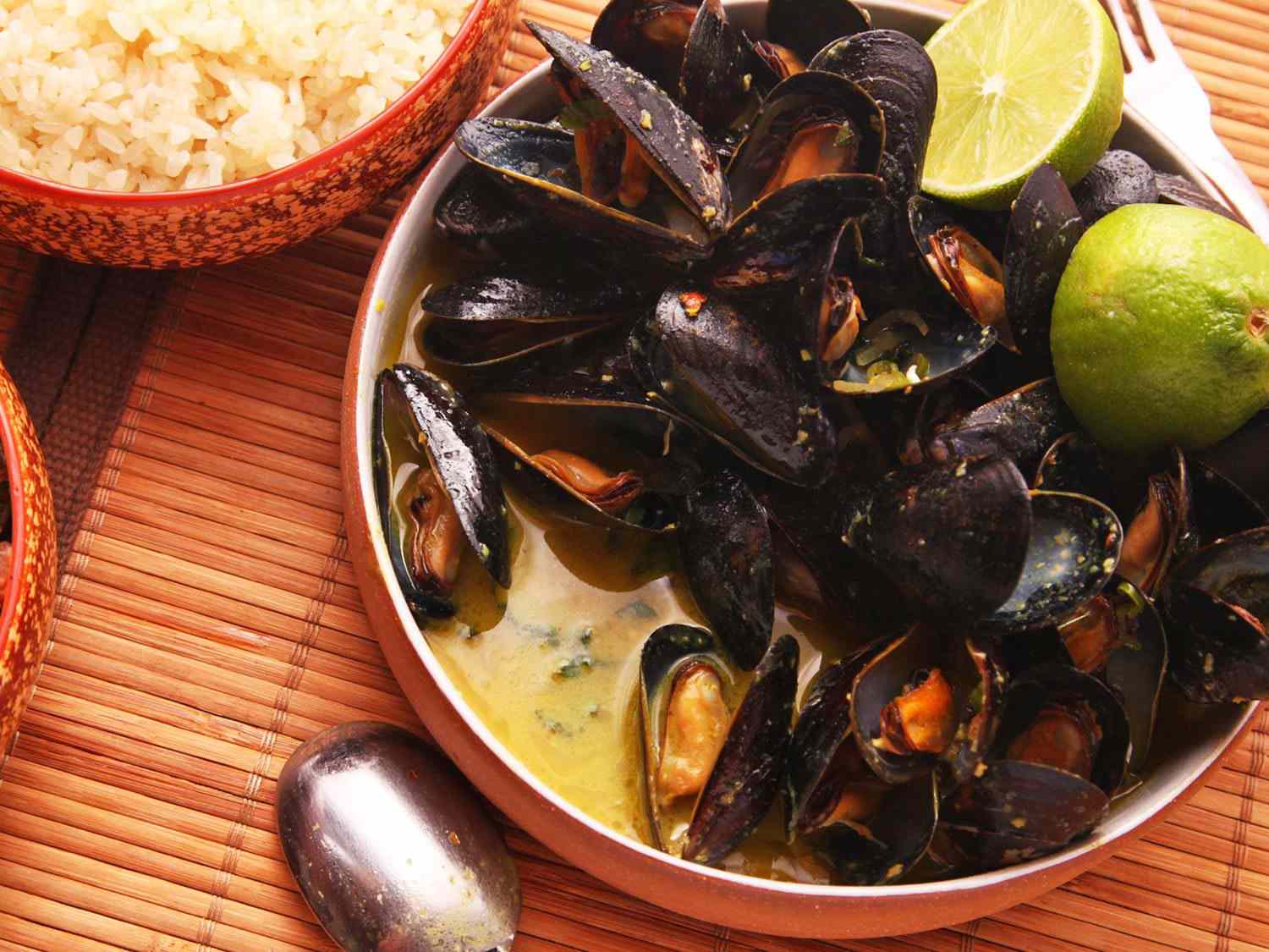 A shallow dish of steamed Thai-style mussels with coconut-curry broth.