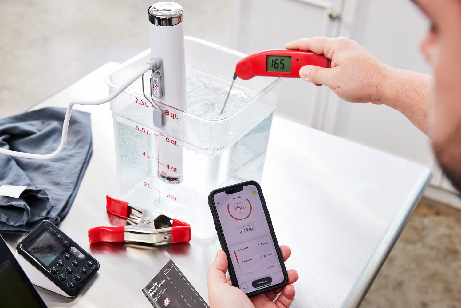 A person using an instant-read thermometer to take the temperature of a sous vide water bath