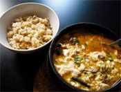 A clay pot filled with soondubu jjigae tofu stew next to rice