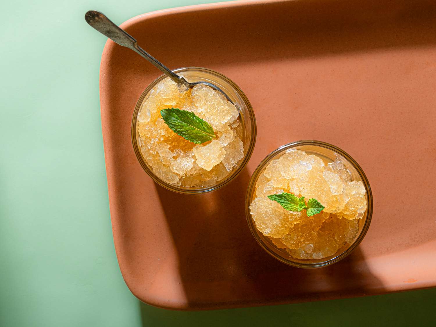 Two glasses of Moroccan mint tea granita on a tray with spoons