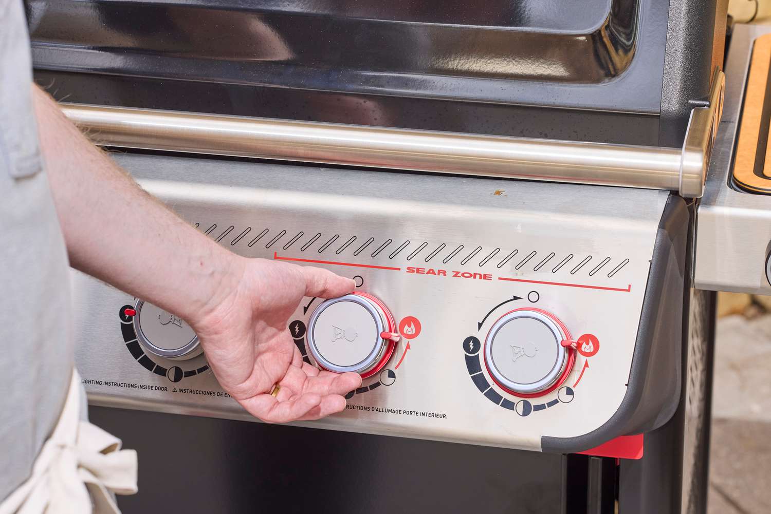 A hand turning the middle nob on the Weber Spirit EP-435 Gas Grill
