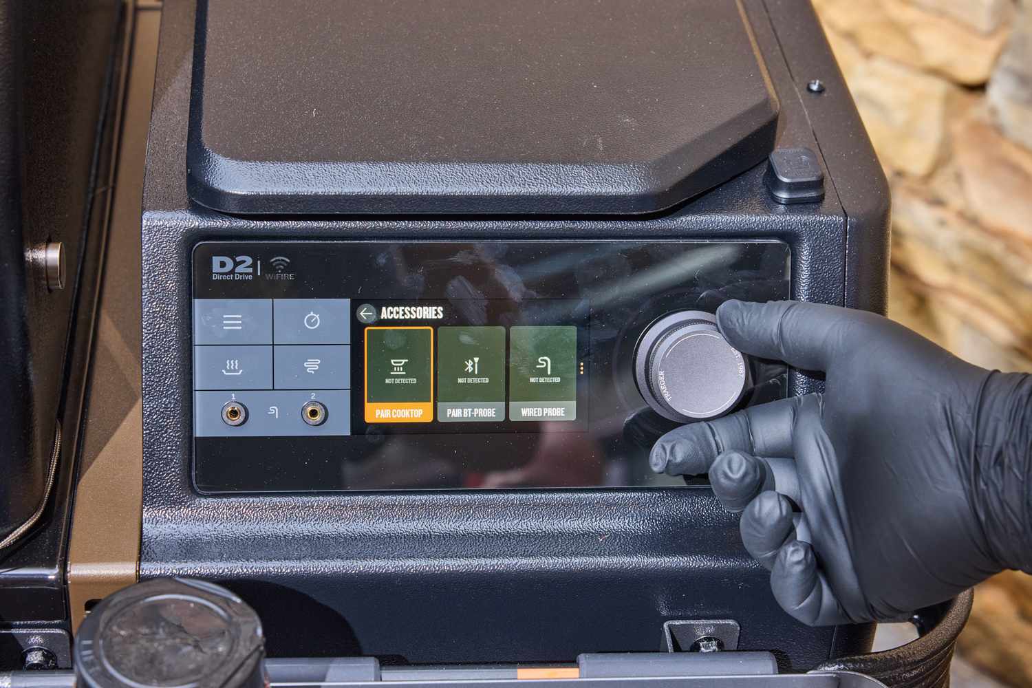 Closeup of a digital control panel with a gloved hand adjusting a knob
