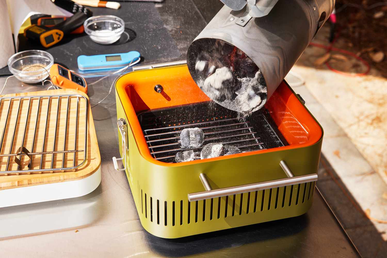 Bin pouring charcoal into the Everdure Cube Portable Charcoal Grill 