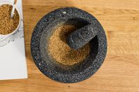 A molcajete with crushed coriander seeds in it.