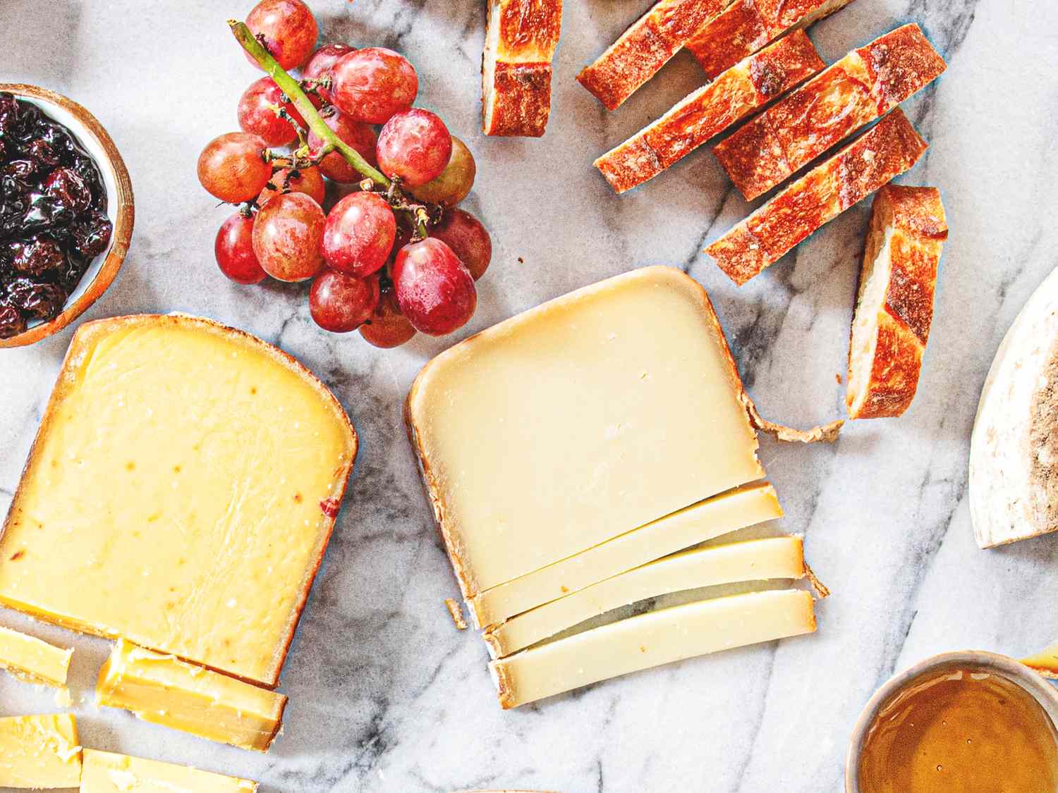 Cheese slices with grapes bread and spreads on a marble surface
