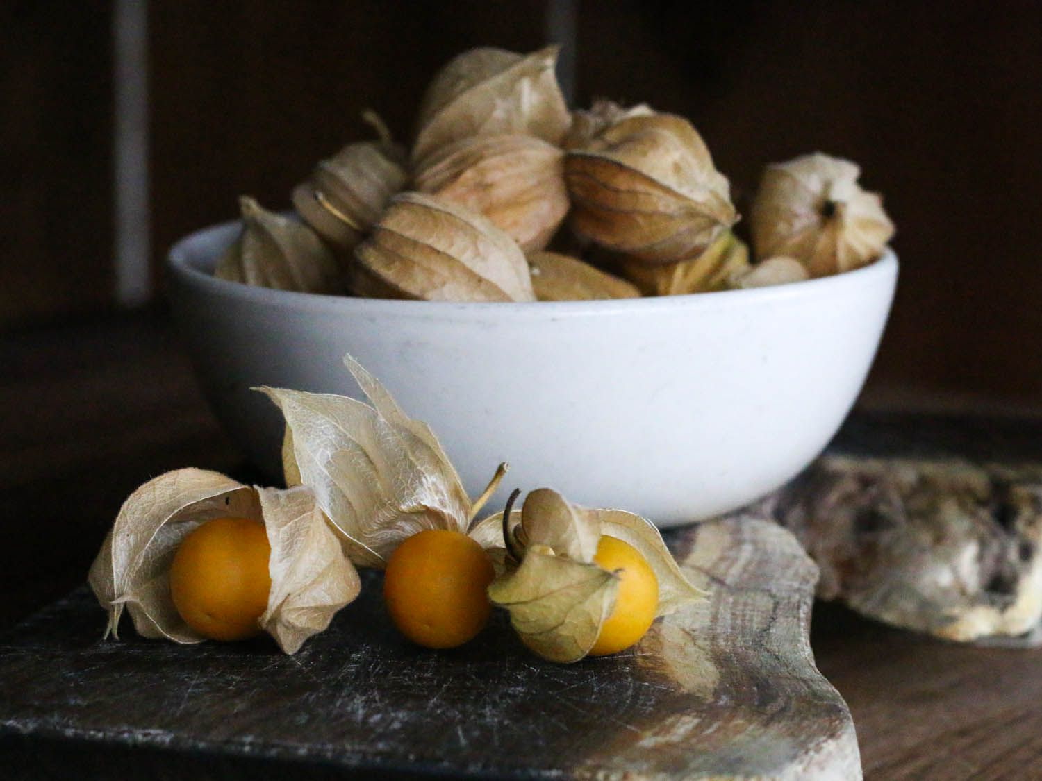 A white bowl filled with cape gooseberries enclosed in papery shells