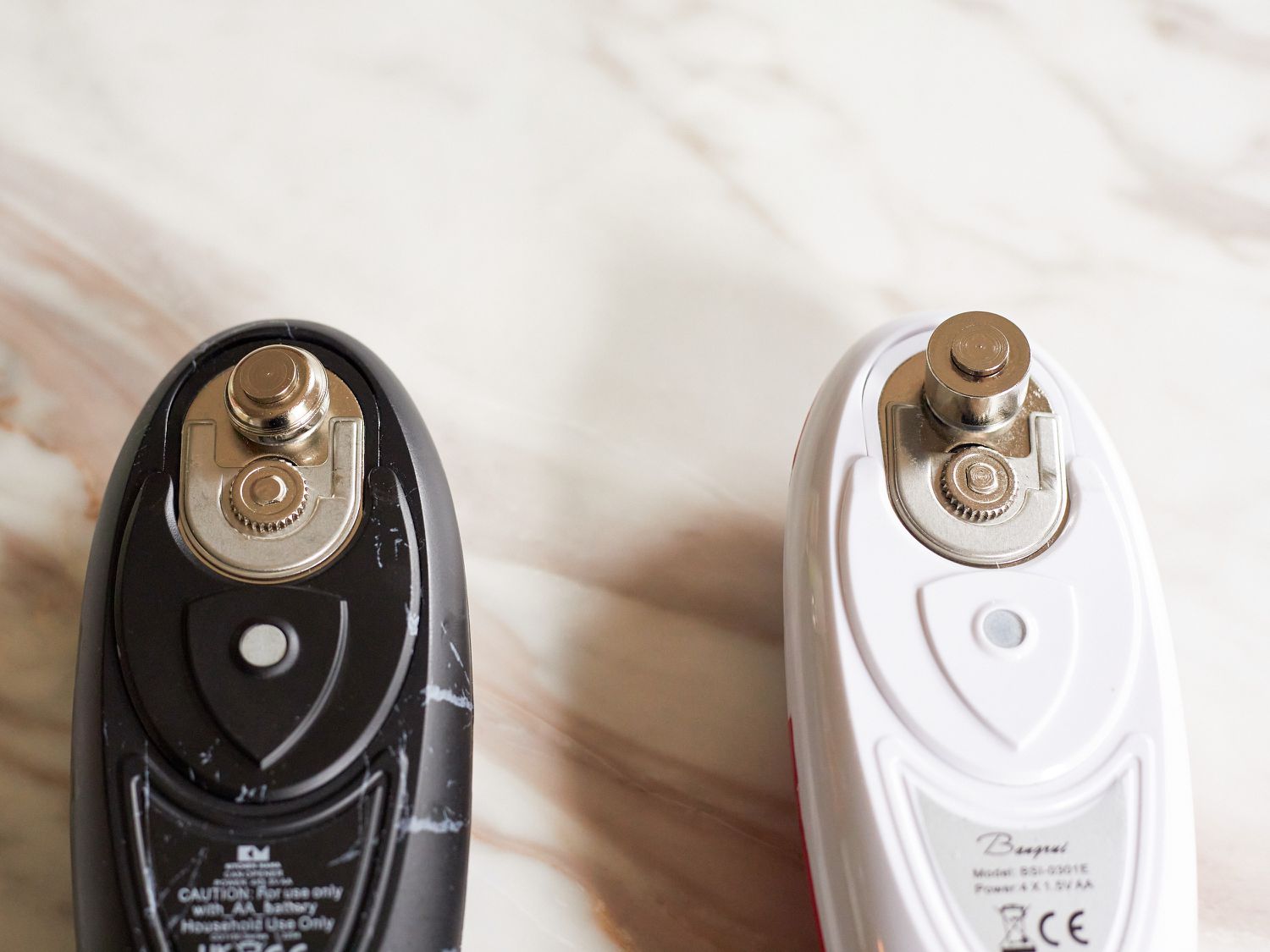 A Kitchen Mama Electric Can Opener next to another can opener on a marble table