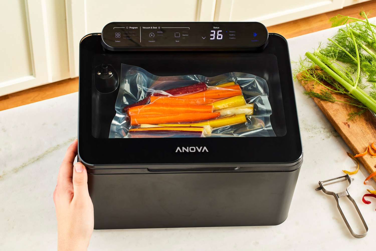 A person vacuum seals carrots in the Anova Precision Chamber Vacuum Sealer