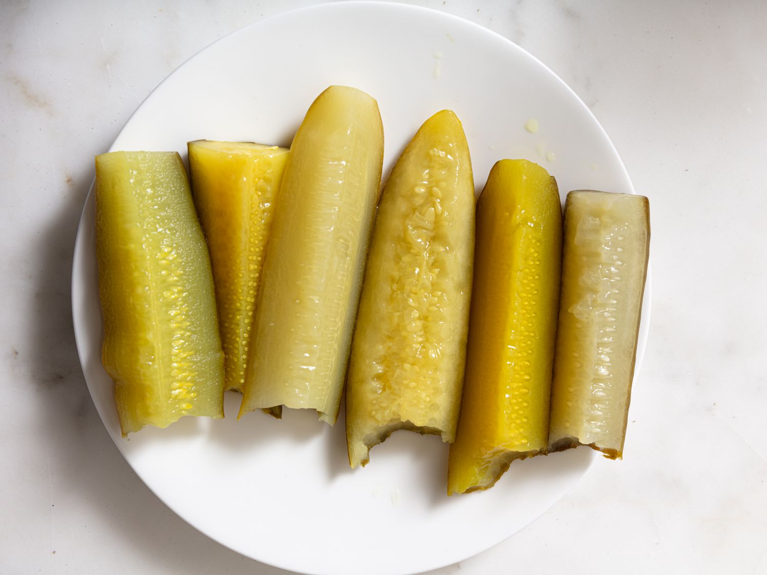 pickles with bites taken out of them lined up on a plate