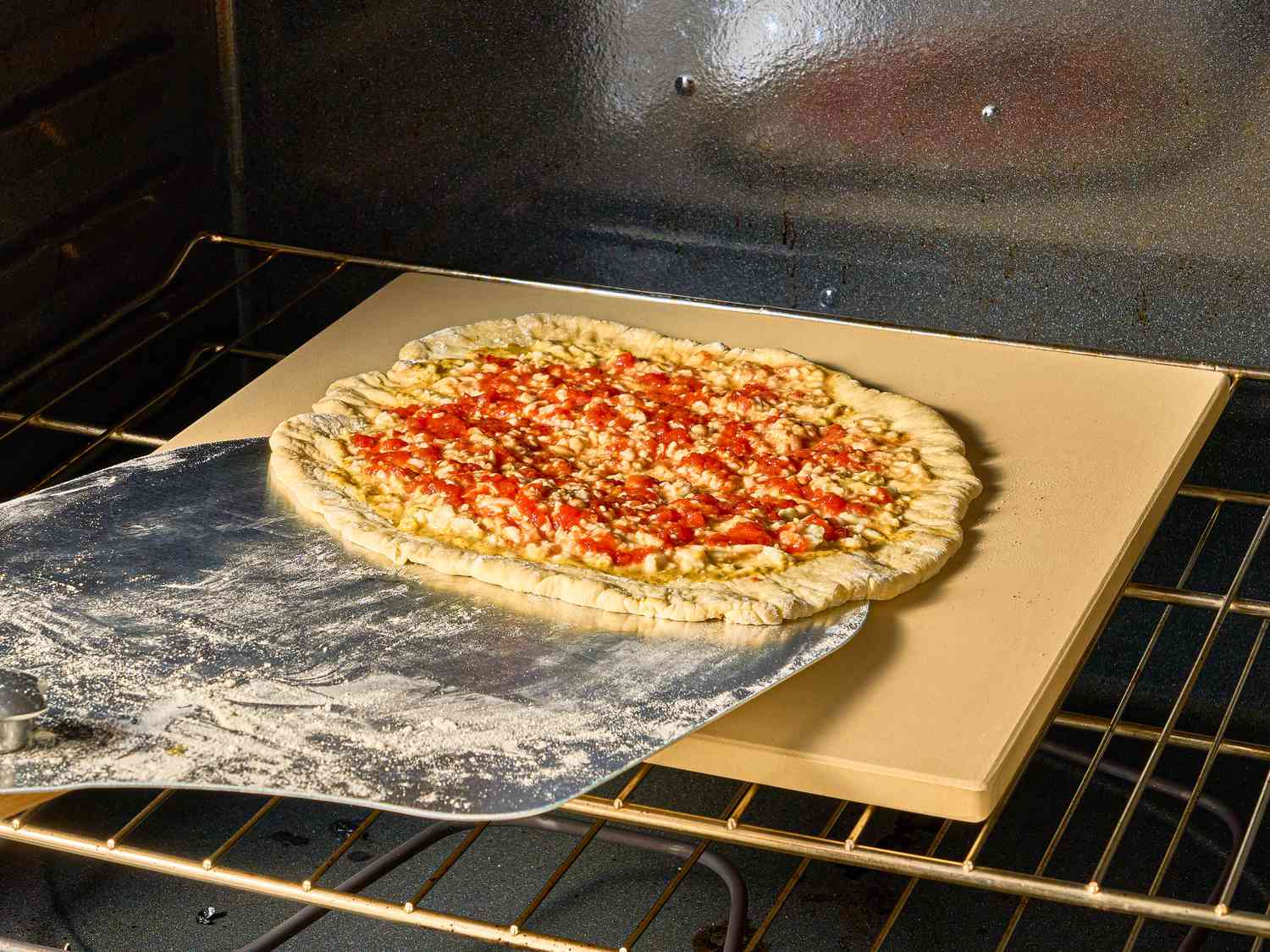 sliding pizza onto pizza stone in oven 