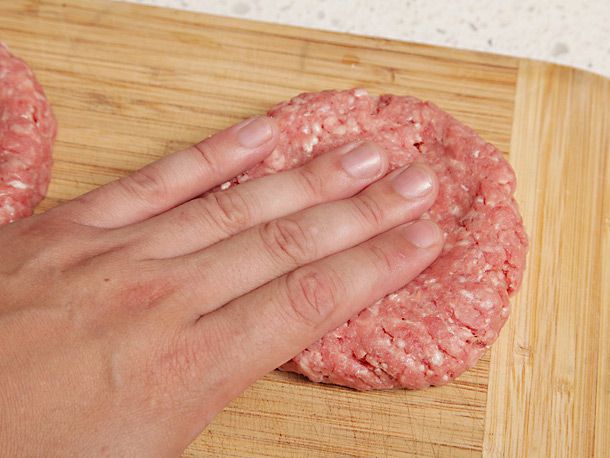 Forming a beef patty and pressing the center of each patty to make a slight indentation.