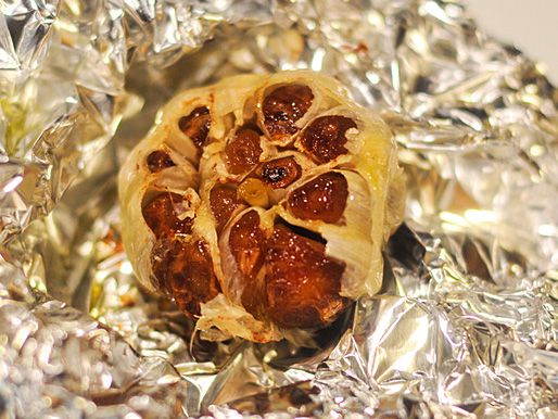 Closeup of a head of roasted garlic, ready to squeeze into a bowl.