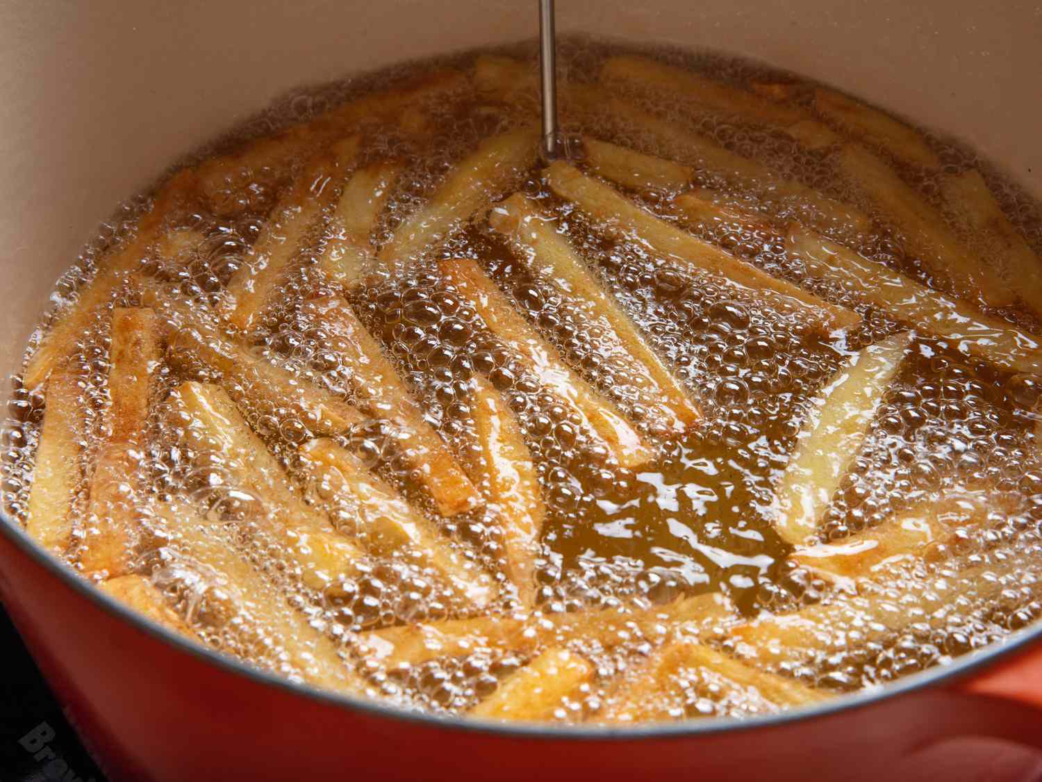 On their third fry, the thick-cut French fires can be seen darkening to a deeper golden color.