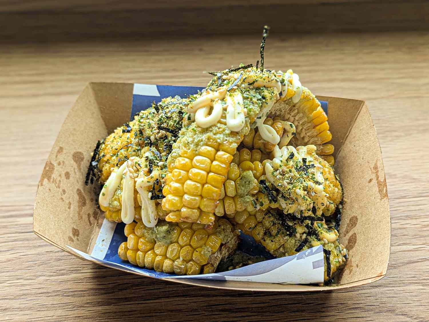 Corn salad mix topped with seasonings and drizzle served in a cardboard container
