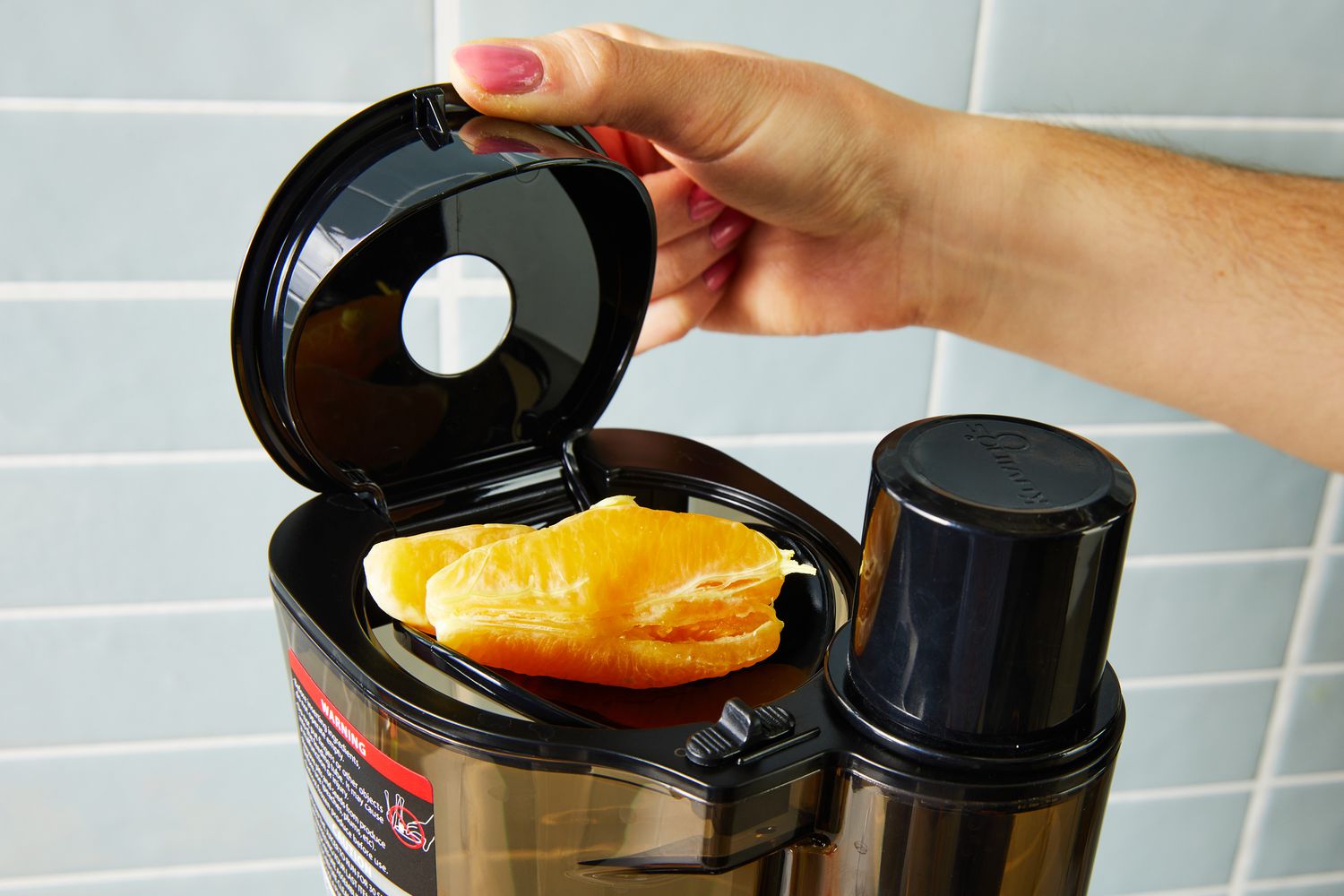 Person putting fruit inside a Kuvings REVO830 Whole Slow Juicer
