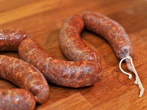 Links of raw chorizo resting on a wooden work surface.