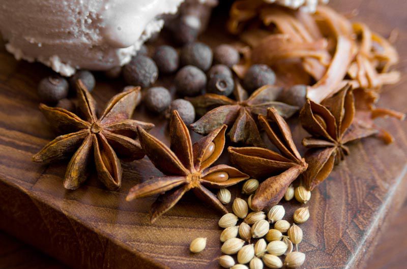 Close-up of assorted whole spices for mulled wine ice cream: star anise, coriander, mace, and allspice berries.