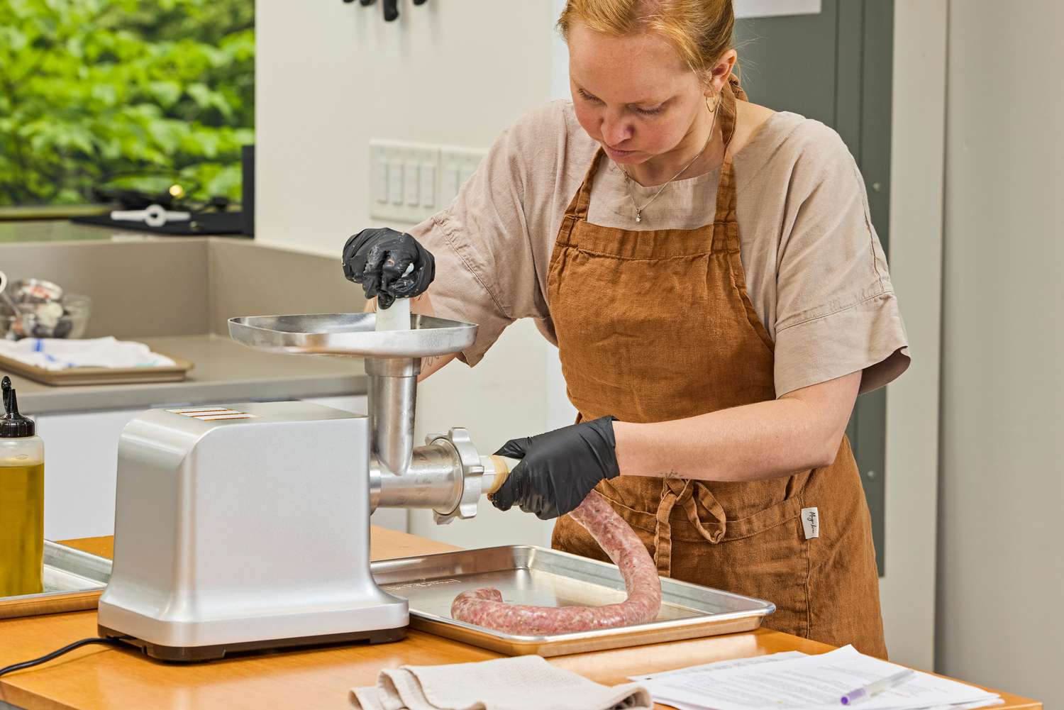 Person making sausage using Weston #12 Electric Meat Grinder & Sausage Stuffer while pushing meat from tray