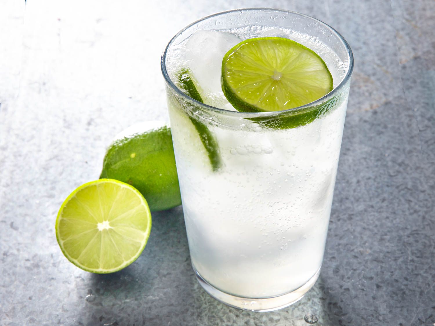 A sweating glass of cold nimbu soda with large slices of fresh lime.
