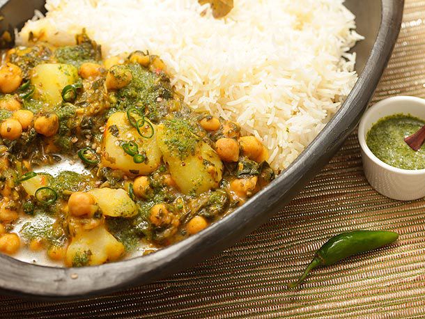 Closeup of chickpea, potato, and spinach jalfrezi, served in a bowl with rice.