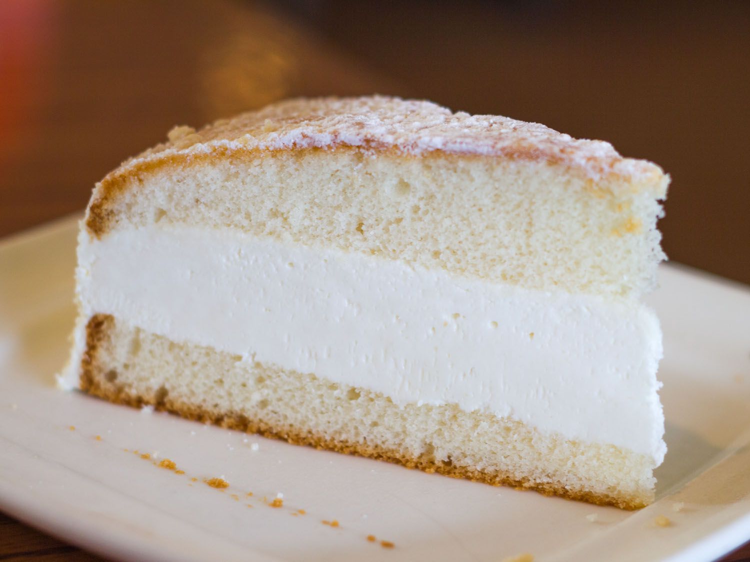 A slice of Lemon Cream Cake on a white plate