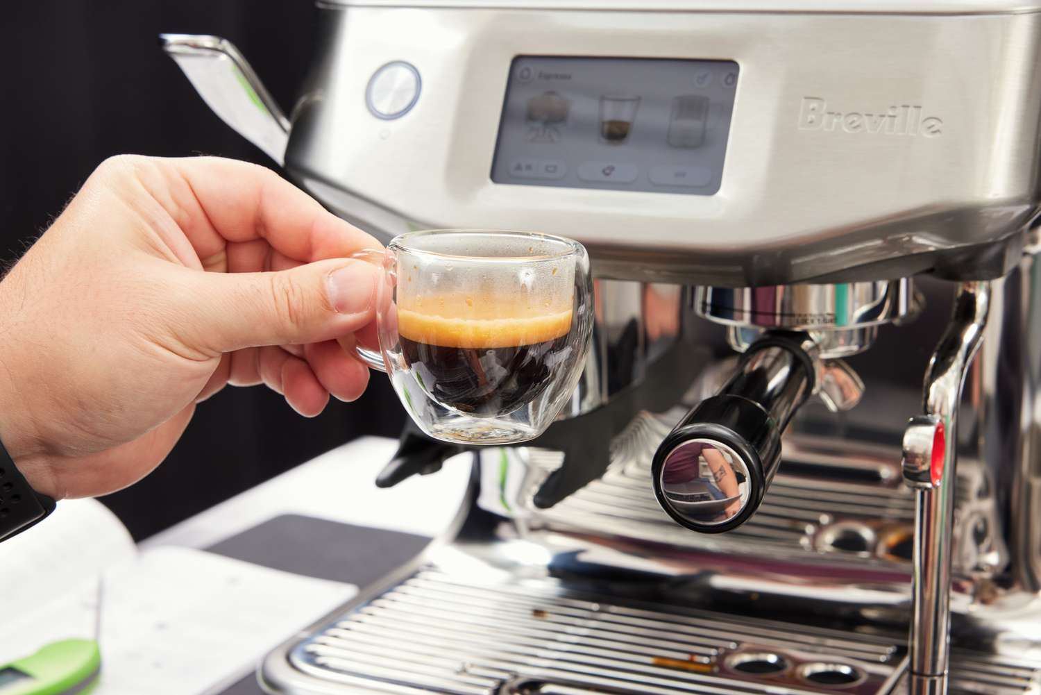 A person holding up a shot of espresso that was brewed from the Breville Barista Touch Impress Espresso Machine with Grinder