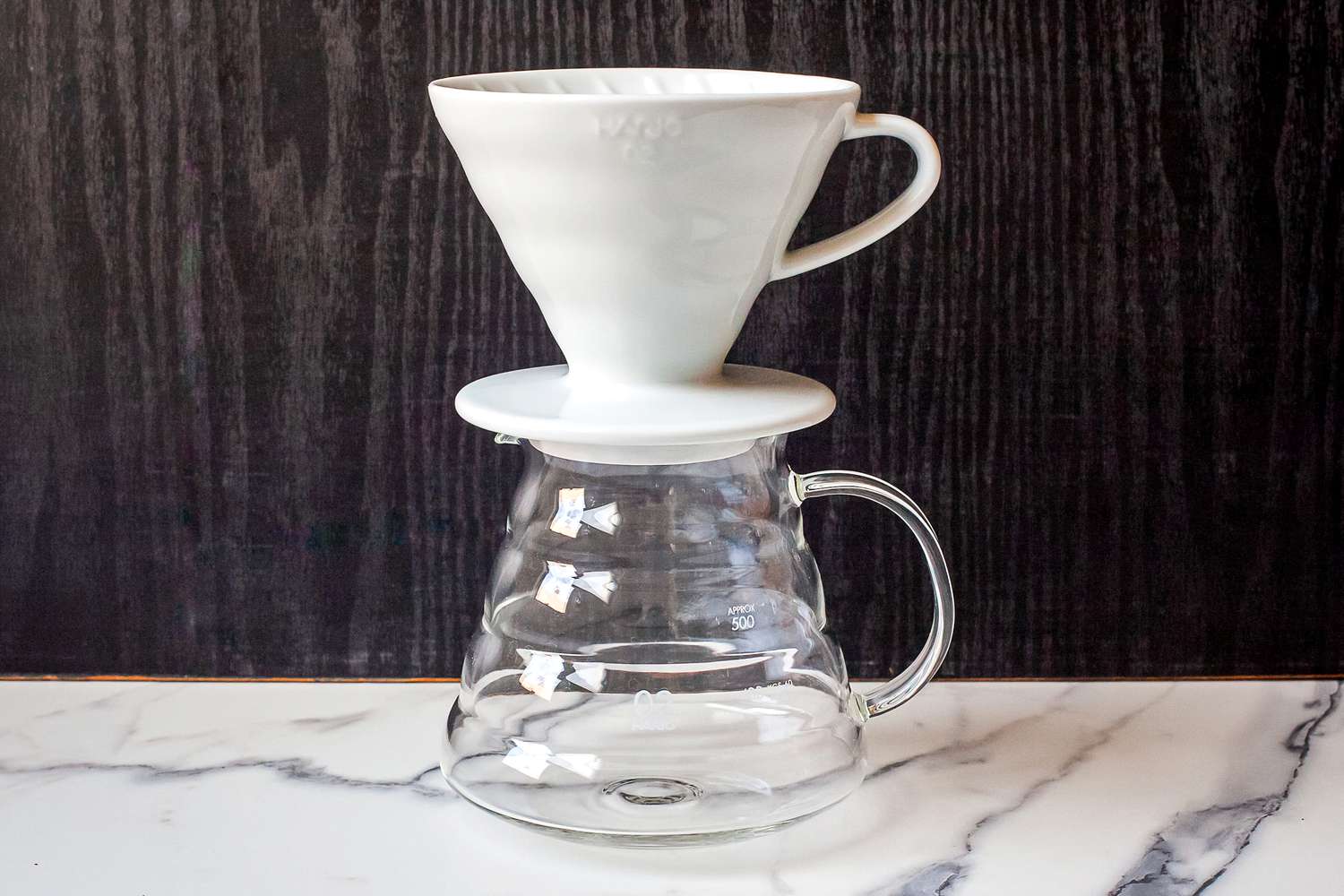 A ceramic coffee dripper positioned on a glass carafe