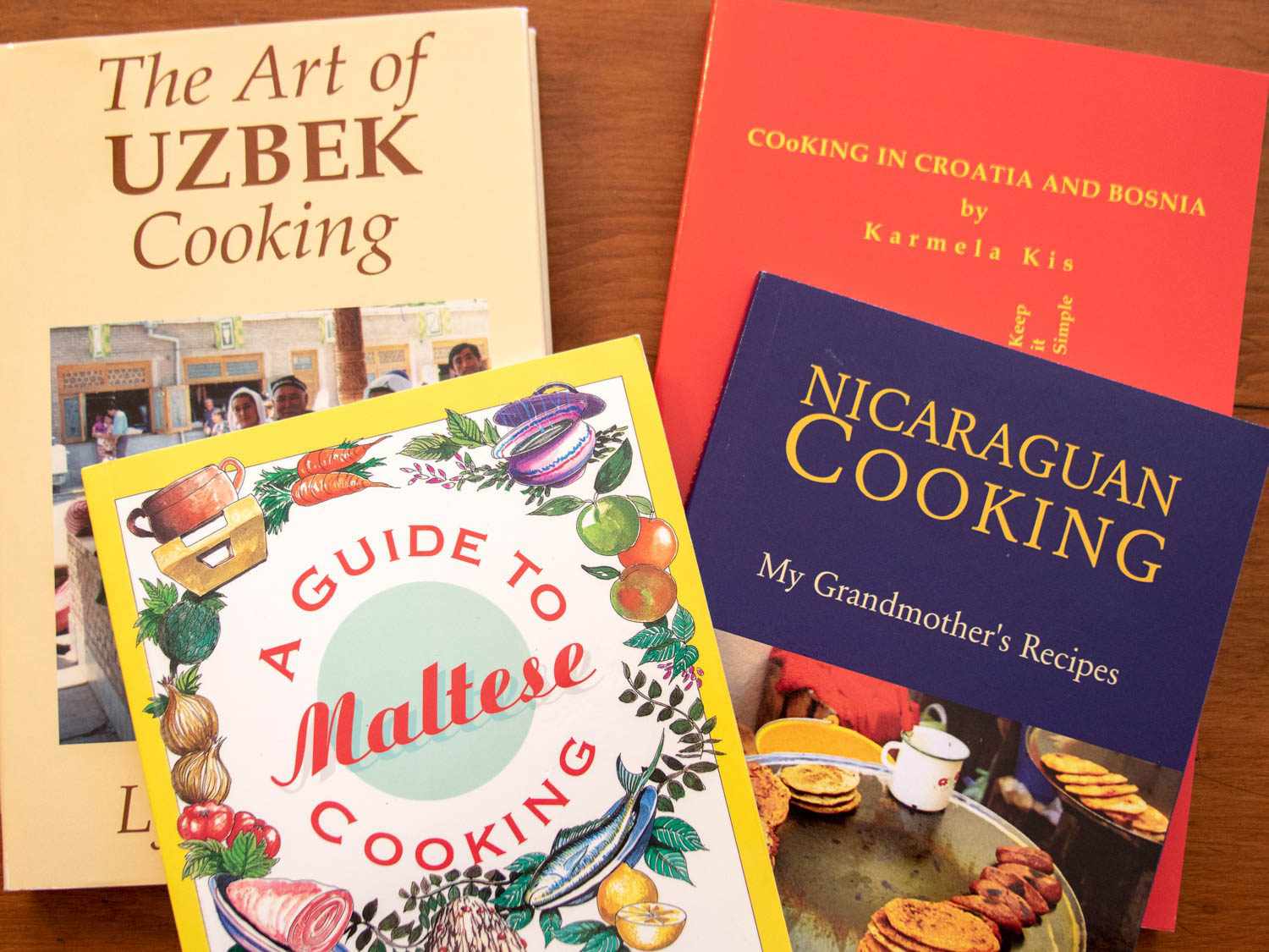 A selection of covers of cookbooks from Sue Jimenez's collection: The Art of Uzbek Cooking, A Guide to Maltese Cooking, Cooking in Croatia and Bosnia, and Nicaraguan Cooking: My Grandmother's Recipes.