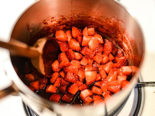 Diced strawberries are stirred in a saucepan with balsamic vinegar and sugar.