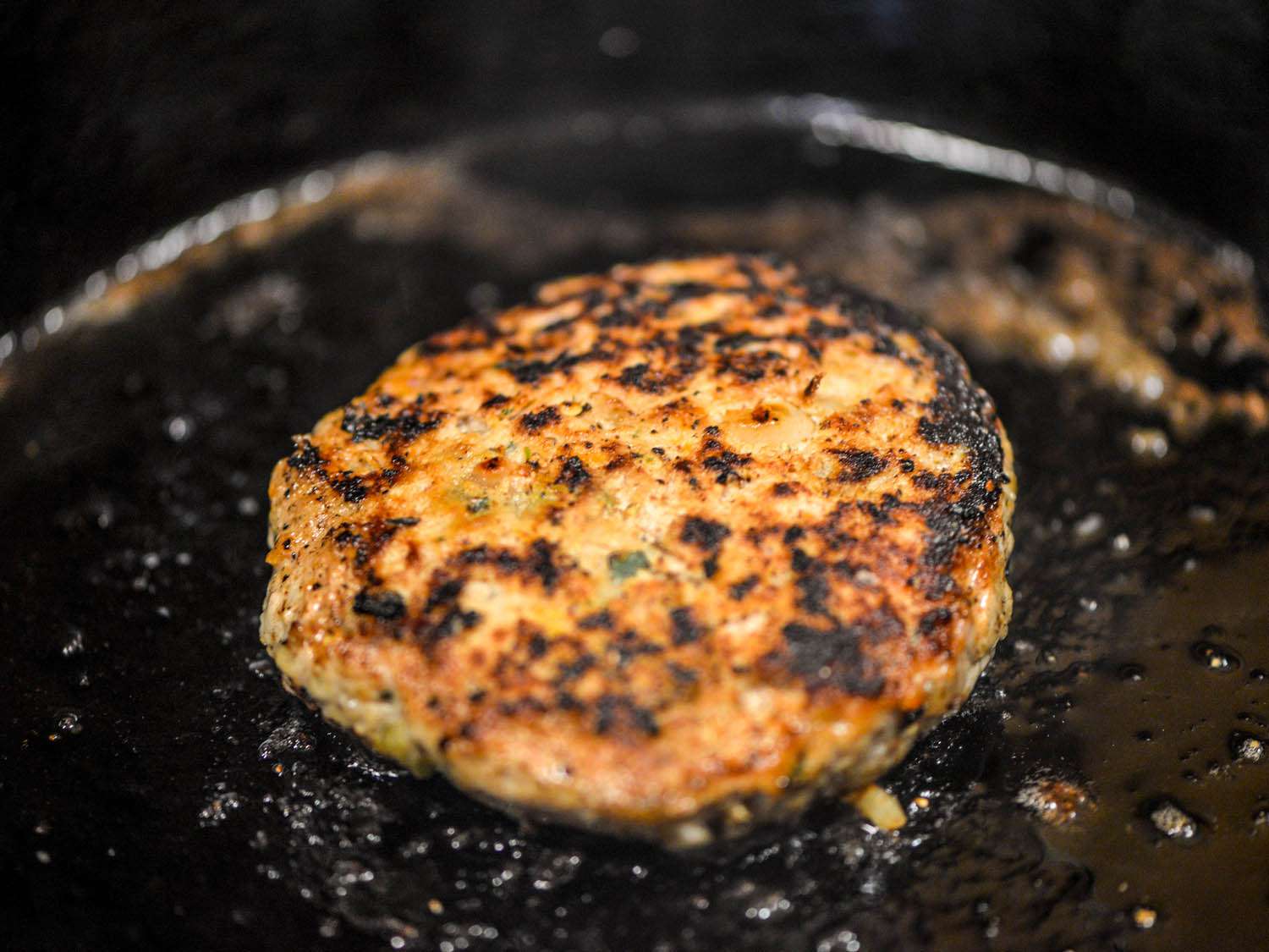 Cooking turkey burger patty in a cast-iron skillet.