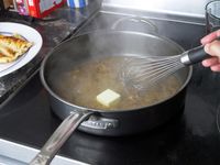 person whisking butter into a saute pan 