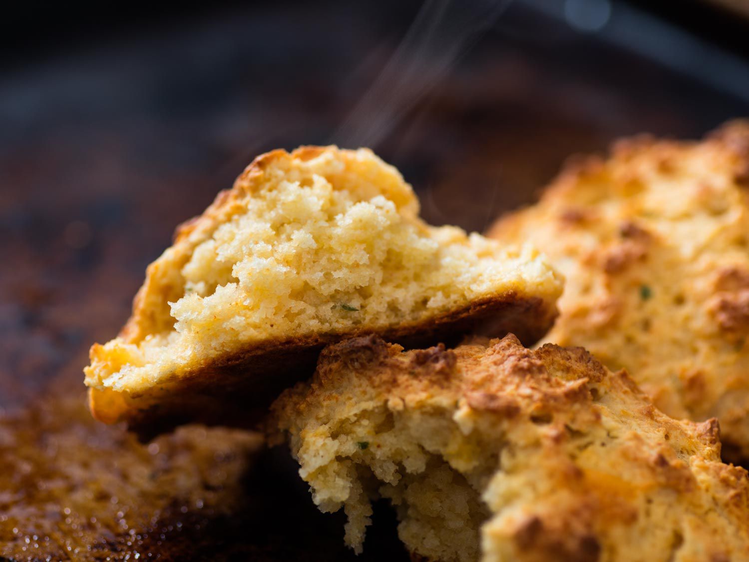 Close-up of a drop biscuit, fresh from the oven and broken in half to reveal a tender crumb.