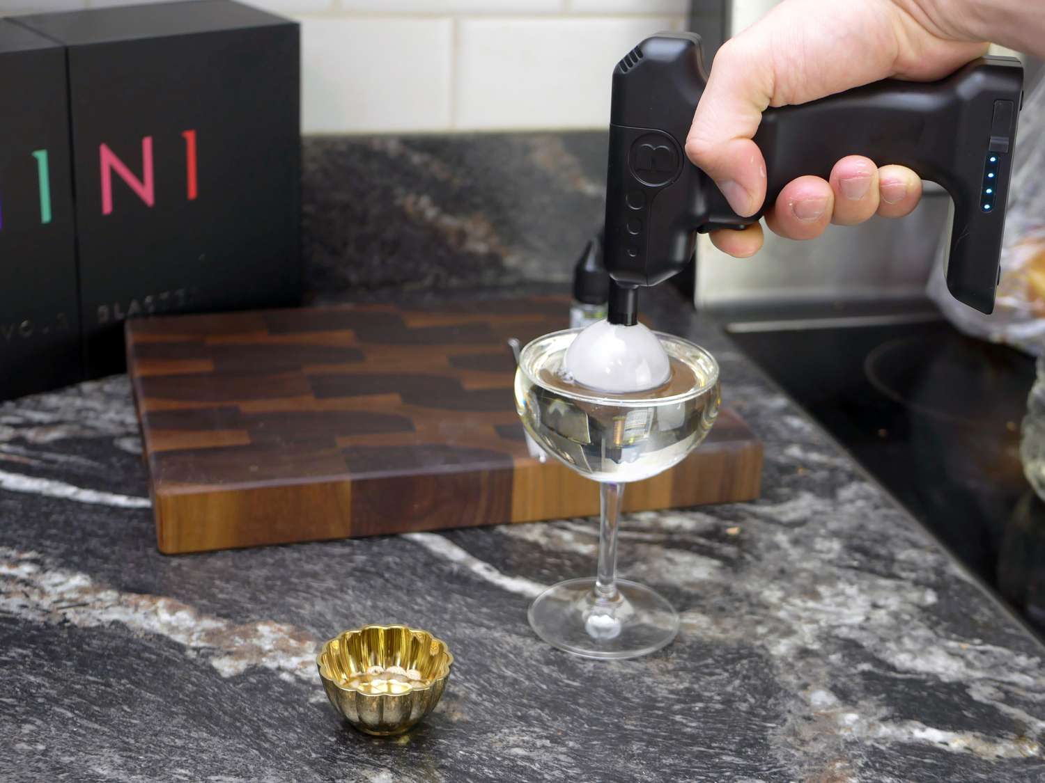 a hand using the flavour blaster mini to blow a scented bubble in a drink