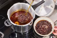 A person spoons beans from the IMUSA 7 Quart Stovetop Aluminum Pressure Cooker