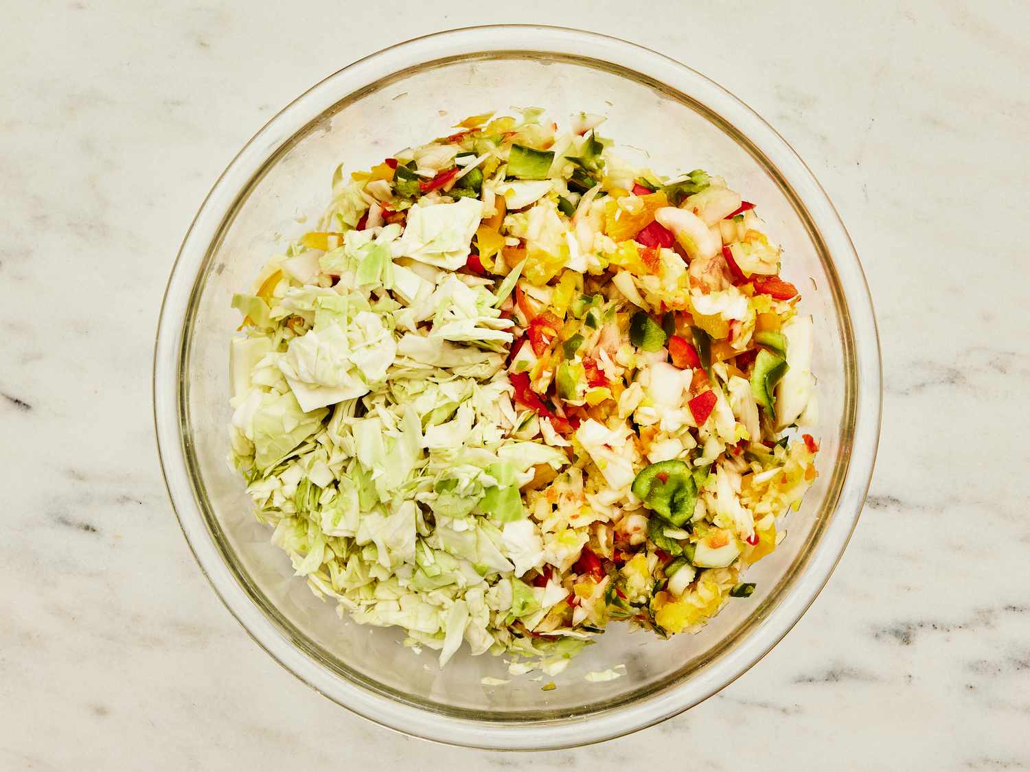 Bowl of ingreadients or Chow Chow and cabbage in a glas bowl on a marble tabletop 