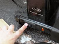 a person turning on the coffee maker. 