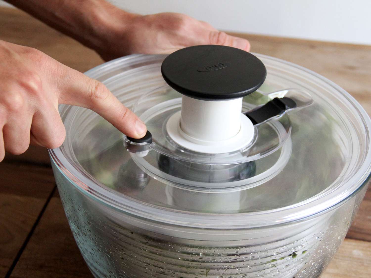 A glass salad spinner in use