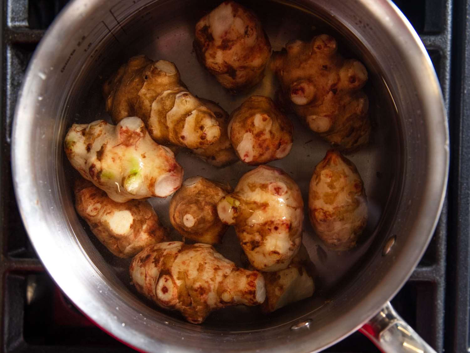 Overhead shot of a pot of water with whole trimmed sunchokes in it